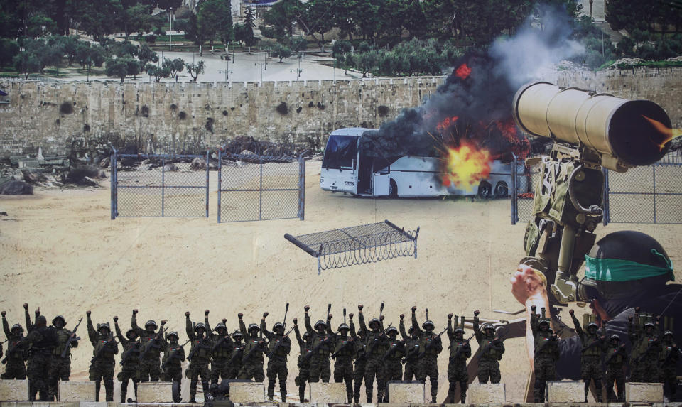 Masked gunmen of the al-Qassam brigades, the military wing of Hamas, raise their hands as they stand in front of a huge poster showing a mock attack on a bus, during a mass rally marking the 31st anniversary of the founding of Hamas, an Islamic political party, that currently rules in Gaza, Sunday, Dec. 16, 2018, in Gaza city. (AP Photo/Khalil Hamra)