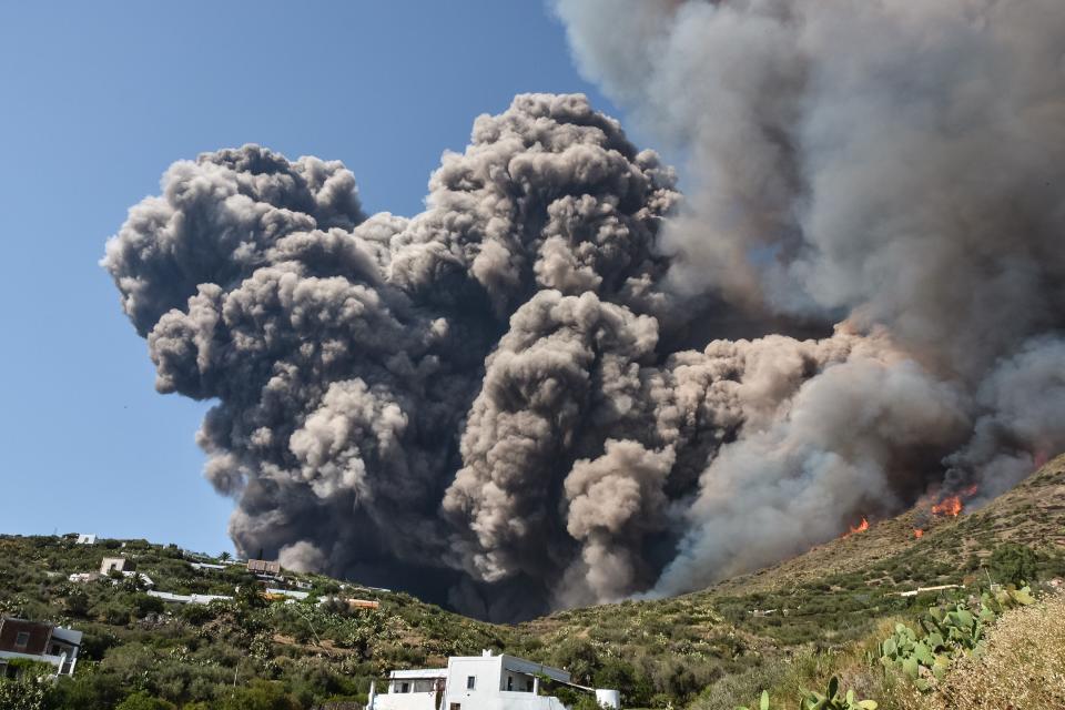 Smoke billows and flames propagate across the hillside near houses after the Stromboli volcano erupted on July 3, 2019.