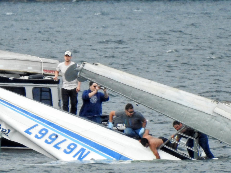 This Monday, May 20, 2019 photo provided by Aerial Leask shows good Samaritans off of fishing vessels attempting to bring in a floatplane that crashed in the harbor of Metlakatla, Alaska. Officials said the pilot and passenger aboard the plane died, and the National Transportation Safety Board is investigating the crash. (Aerial Leask via AP)