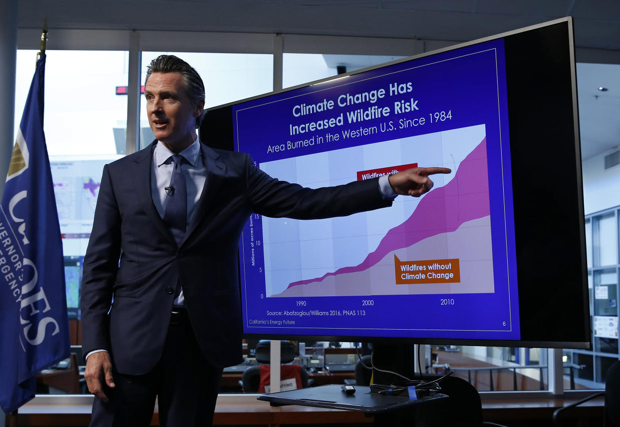 Democratic California Gov. Gavin Newsom points to a graph showing the increased risk of wildfires due to climate change during a news conference in Rancho Cordova, Calif.