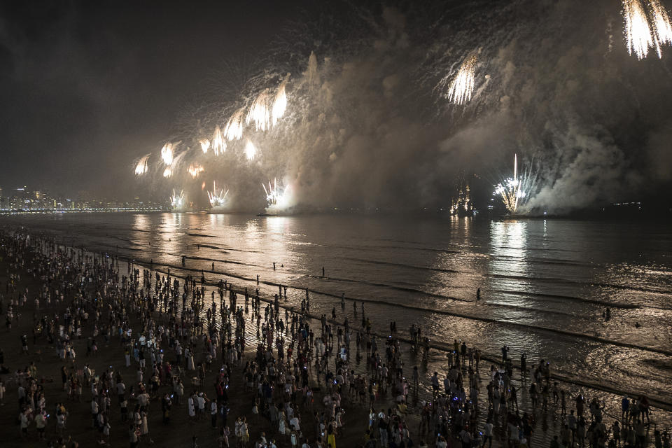 People bring in the New Year as they watch fireworks explode over Santos Bay, in Santos, Brazil, early Sunday, Jan. 1, 2023. (AP Photo/Matias Delacroix)