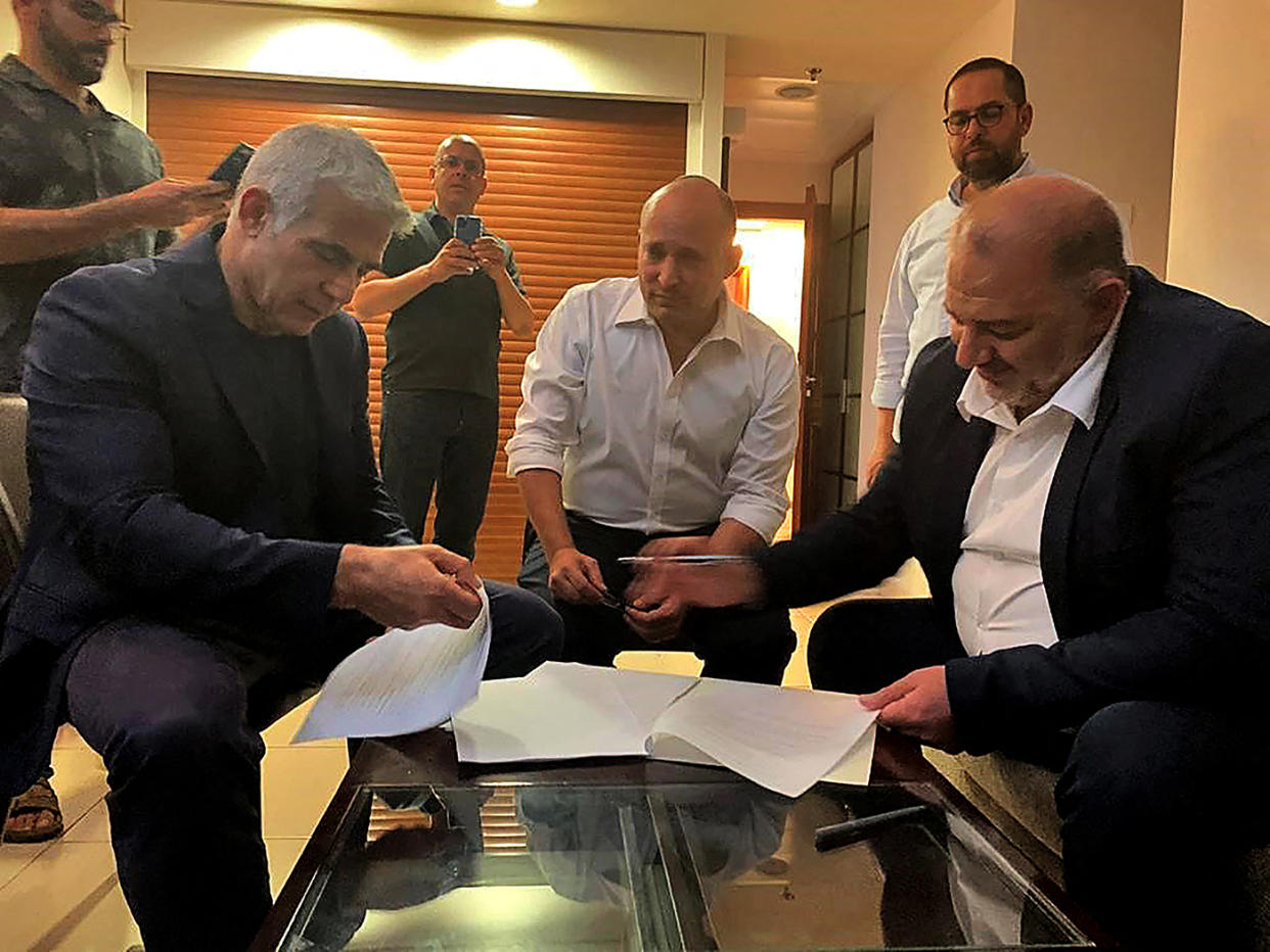 A handout picture provided by the United Arab List on June 2, 2021, shows Mansour Abbas, right, signing a coalition agreement with Israel's opposition leader Yair Lapid, left, and right-wing nationalist Naftali Bennett in Ramat Gan near the coastal city of Tel Aviv.