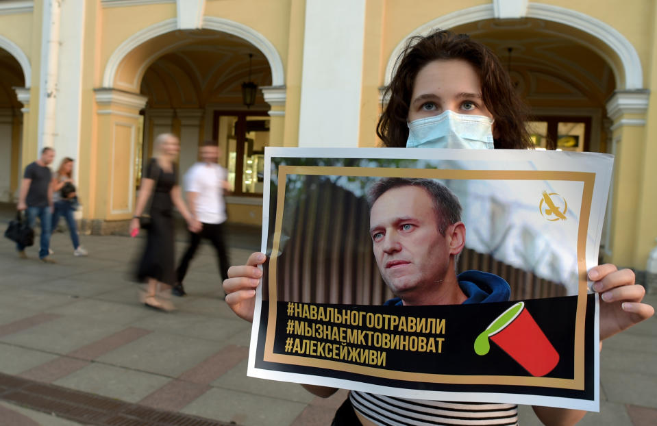 A woman holding a placard with an image of Alexei Navalny expresses support for the opposition leader after he was rushed to intensive care. Source: Getty