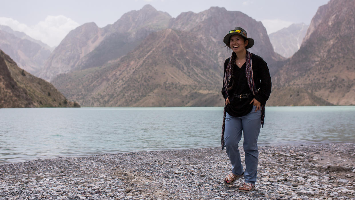  A woman wearing Patagonia Women’s Chambeau Rock Pants stands at the edge of a lake, with mountains in the background. 