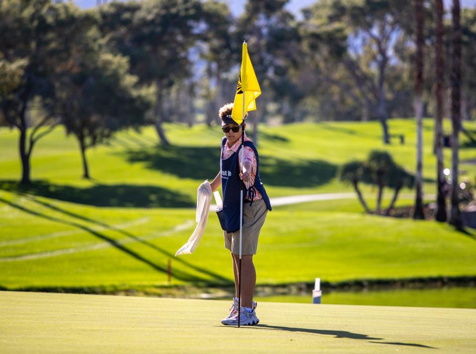 First Tee caddie Amar’e Mullen, 14, pulls the flag from the cup on the first green for his group at Ironwood Country Club in Palm Desert, Calif., Saturday, Nov. 18, 2023.