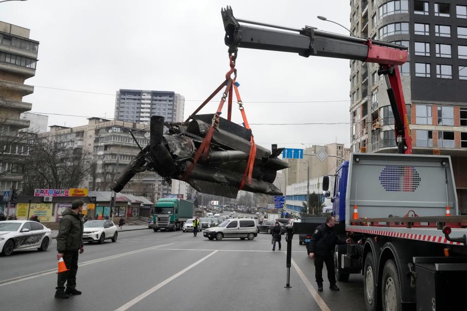 Workers load the debrs a rocket onto a truck in the aftermath of an apparent Russian strike in Kyiv, Ukraine, Thursday, Feb. 24, 2022.