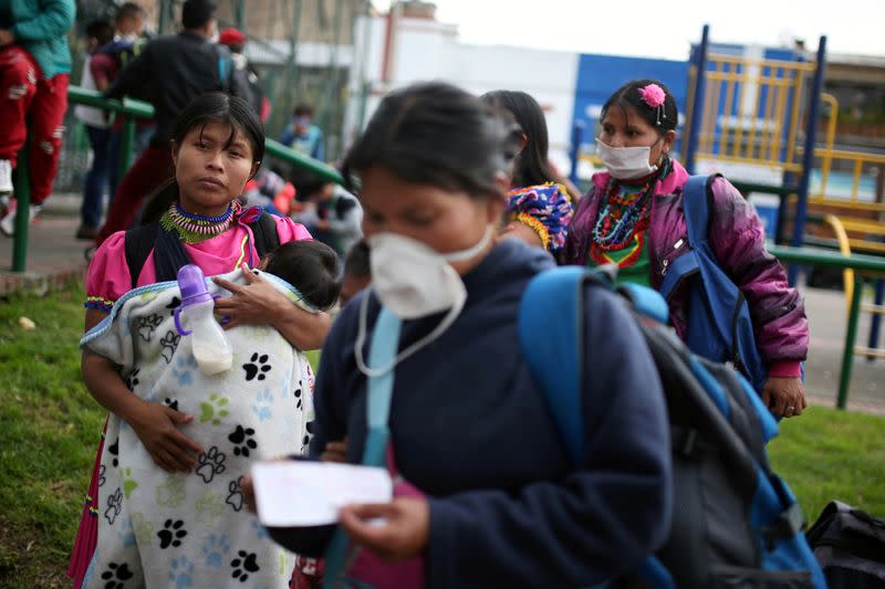 Indigenous people wearing protective face masks as a preventive measure against the spread of the coronavirus disease (COVID-19) carry their belongings after being evicted from a building in Bogota