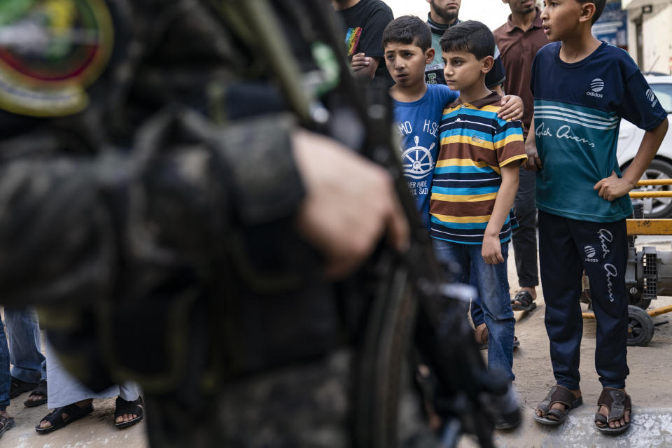 Children watch as Hamas militants parade through the streets for Bassem Issa, a top Hamas' commander, who was killed by Israeli Defense Force military actions prior to a cease-fire reached after an 11-day war between Gaza's Hamas rulers and Israel, in Gaza City, Saturday, May 22, 2021. (AP Photo/John Minchillo)