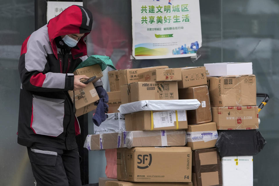 A worker of a private delivery company picks up parcels at its distribution center in Beijing, Sunday, Nov. 7, 2021. China's exports remained strong in October, a positive sign for an economy trying to weather power shortages and COVID-19 outbreaks. (AP Photo/Andy Wong)