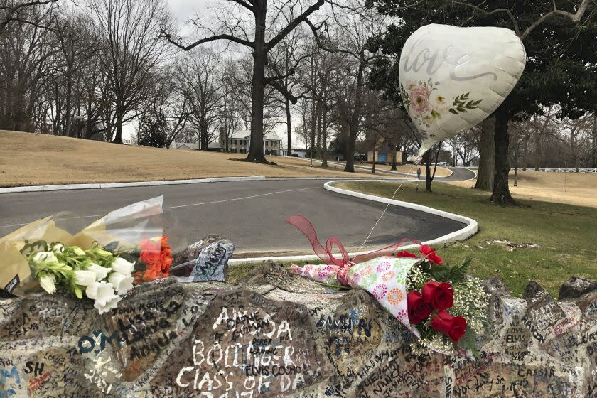 Bouquets of flowers and balloons laying on a rock on the side of a road