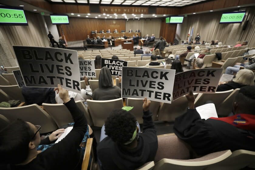 TORRANCE, CA -- DECEMBER 10, 2019: Protestors with signs attend the Torrance City Council meeting one year after the police shooting death of Christopher De'Andre Mitchell. (Myung J. Chun / Los Angeles Times)