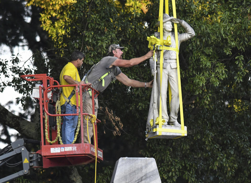The Confederate statue located in the Circle at the University of Mississippi is lowered to the ground as part of the process to move it to the Confederate Soldiers Cemetery on campus, in Oxford, Miss. Tuesday, July 14, 2020. (Bruce Newman/The Oxford Eagle via AP)