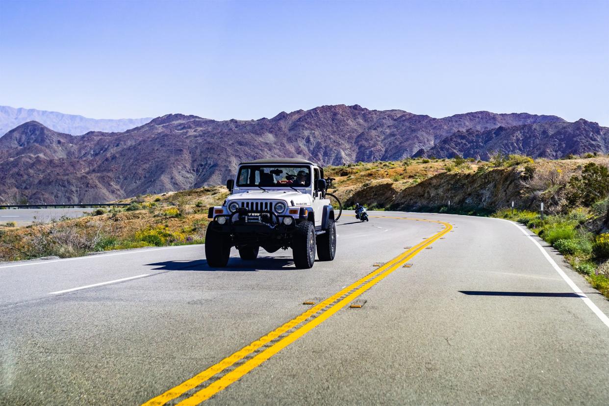 Jeep driving on a highway with mountains in background.