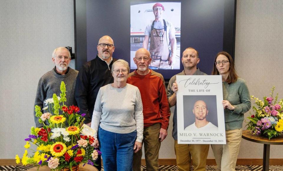 Family members stand around a photograph of Milo Warnock during a celebration of life memorial held for him in Meridian, Jan. 13, 2024. Warnock was killed by a fellow prisoner in the Idaho State Correctional Center in December. Pictured from left: brothers Murray Warnock, Yancey Warnock, mother Kathy Warnock, father Mike Warnock, brother Clinton Warnock and sister Hallie Johnson.