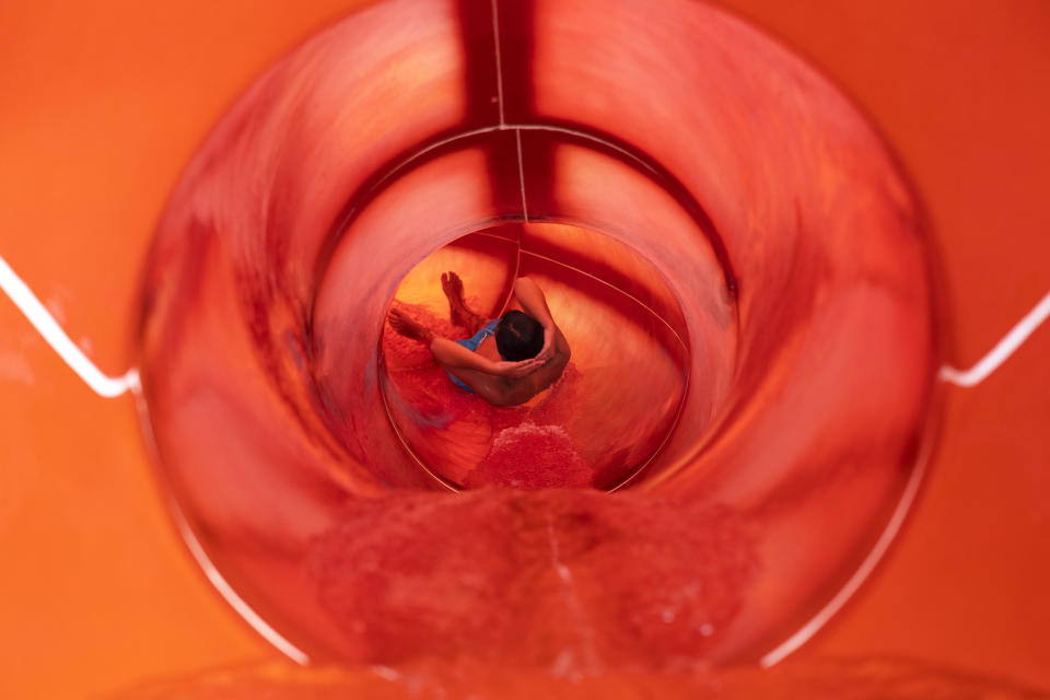 A youth enjoys a water slide at a water park of Spata town, east of Athens, Greece, Sunday, July 23, 2023. Heat in Greece is expected to grow worse during the weekend, approaching 44 Celsius (111 Fahrenheit) and the country will face one more heatwave episode by the end of July. (AP Photo/Yorgos Karahalis)