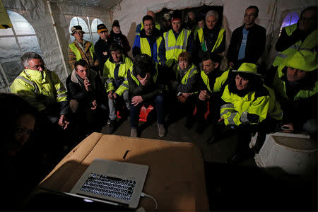 Protesters wearing yellow vests watch French President Emmanuel Macron on a computer screen in Sainte-Eulalie, France, December 10, 2018. REUTERS/Regis Duvignau