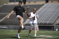 Adam Botkin, a football TikTok influencer, punts the ball while recording a video for a post with Brandin Evans, right, at Washington-Grizzly Stadium in Missoula, Mont., on Monday, May 1, 2023. Botkin, a former walk-on place kicker and punter for the Montana Grizzlies, gained notoriety on the social media platform after videos of him performing kicking tricks went viral. (AP Photo/Tommy Martino)