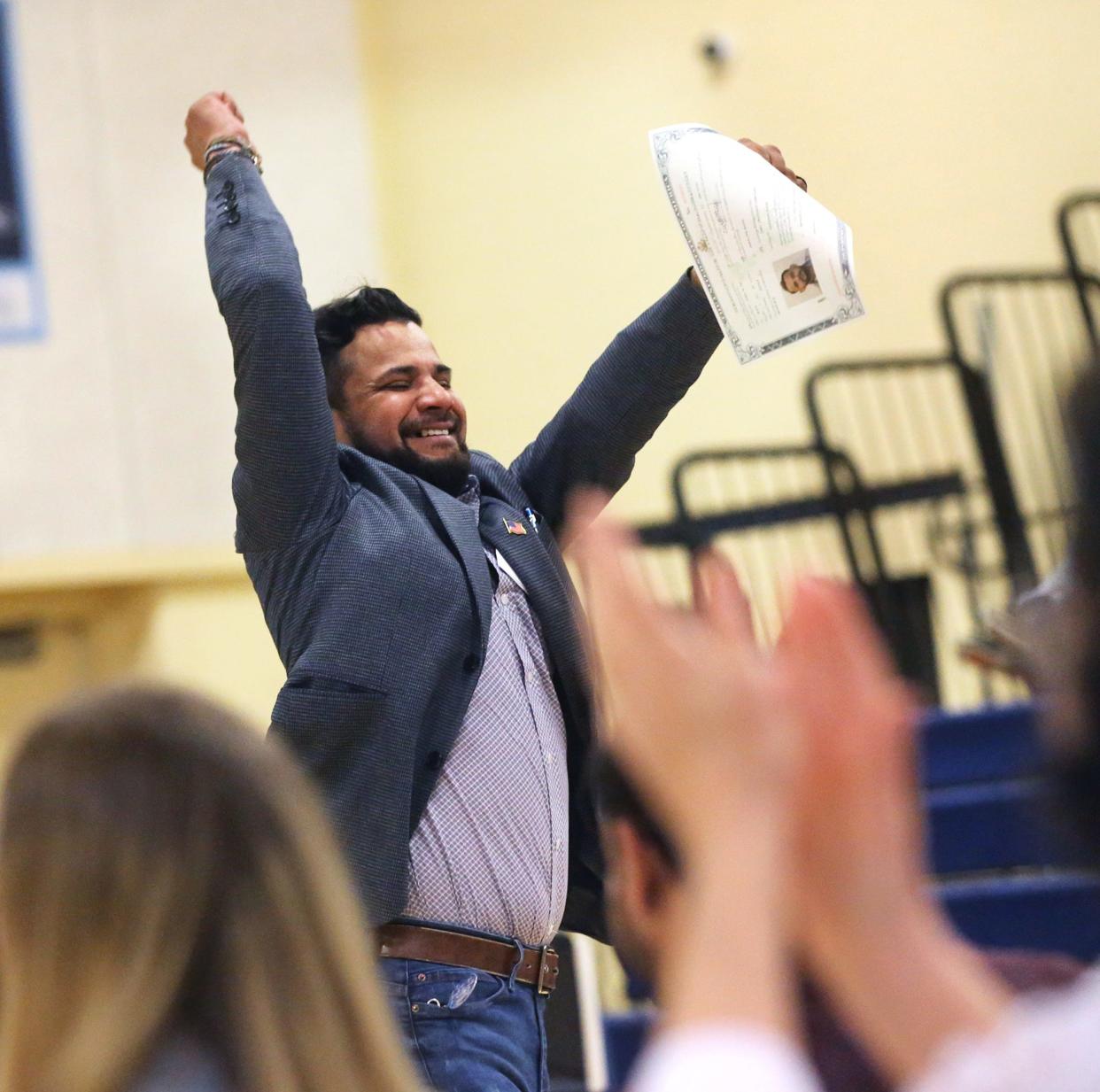 A man jumps for joy after receiving his certificate proving his U.S. citizenship during a naturalization ceremony at Middle School of the Kennebunks May 3, 2024.