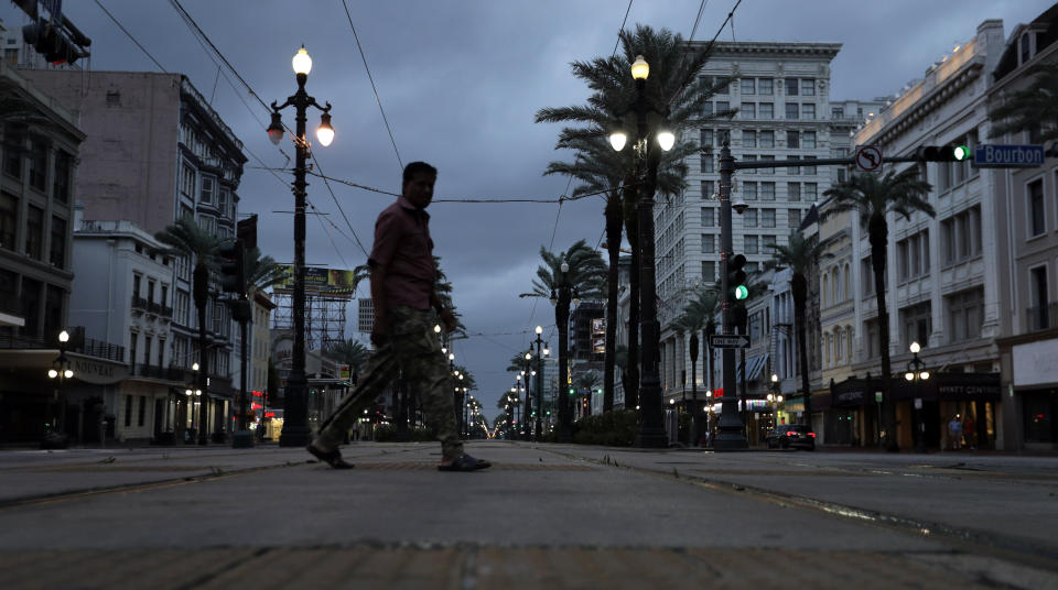 Raghu Das crosses Canal Street on his way to work in the French Quarter Saturday, July 13, 2019, in New Orleans, as Tropical Storm Barry nears landfall. (AP Photo/David J. Phillip)