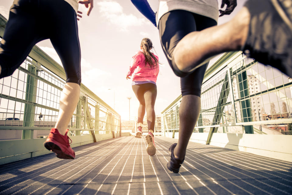 A shot from the ground up of three young people jogging across a bridge.