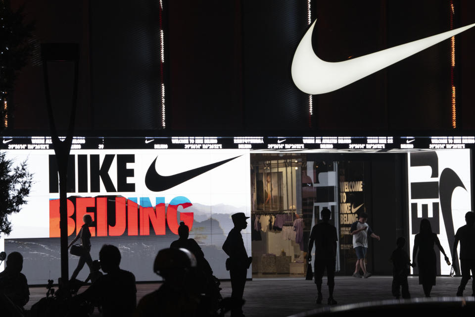 Residents are silhouetted outside a mall in Beijing, Sunday, June 18, 2023. Chinese merchants offered customers steep discounts during China's first major online shopping festival after the COVID-19 pandemic, in the hopes of shoring up sales amid a weaker-than-expected recovery in consumption. (AP Photo/Ng Han Guan)