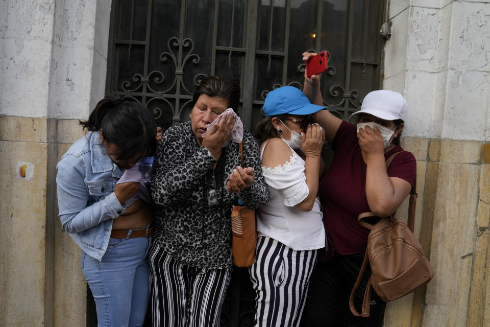 Women take cover from tear gas thrown by police during clashes with anti-government protesters in Lima, Peru, Thursday, Jan. 19, 2023. Protesters are seeking immediate elections, the resignation of President Dina Boluarte, the release from prison of ousted President Pedro Castillo and justice for protesters killed in clashes with police. (AP Photo/Martin Mejia)