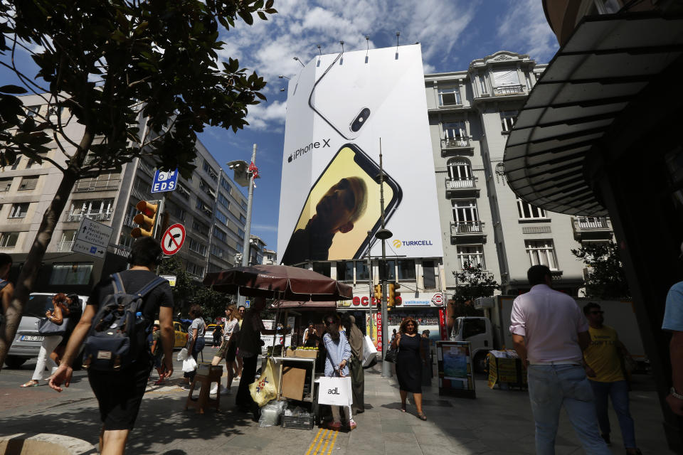 People walk past an advertising billboard for a smartphone in an upscale neighborhood in Istanbul, Turkey, on Wednesday, Aug. 15, 2018. Haydar Tastan, an Istanbul resident shopping for a cell phone, said a boycott of American goods could be a “great thing” but he wished there were alternatives. “I'm not looking for a new product anyway,” he said. “I'm looking for something that's secondhand.” (AP Photo/Lefteris Pitarakis)