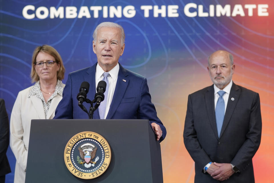 President Biden, flanked by Deanne Criswell and Rich Spinrad, speaks under a banner saying: Combating the Climate.