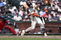 San Francisco Giants' Tyler Fitzgerald, right, hits an RBI single in front of Washington Nationals Drew Milas, left, during the first inning of a baseball game in San Francisco, Wednesday, April 10, 2024. (AP Photo/Jed Jacobsohn)