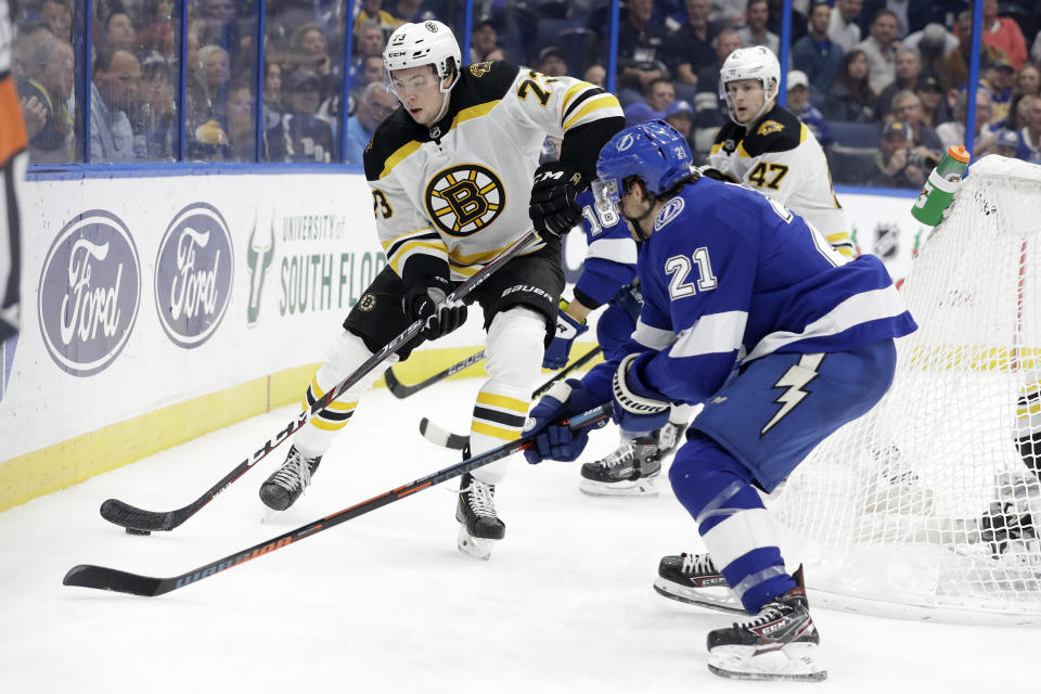 Boston Bruins defenseman Charlie McAvoy (73) looks to move the puck past Tampa Bay Lightning center Brayden Point (21) during the second period of an NHL hockey game Thursday, Dec. 12, 2019, in Tampa, Fla. (AP Photo/Chris O'Meara)