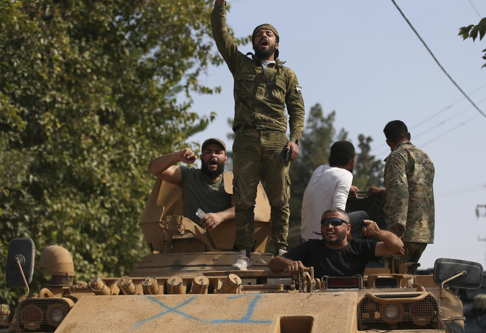 Turkish-backed Syrian opposition fighters on an armoured personnel carrier chant slogans as they wait to cross the border into Syria, in Akcakale, Sanliurfa province, southeastern Turkey, Friday, Oct. 18, 2019. Fighting continued in a northeast Syrian border town at the center of the fight between Turkey and Kurdish forces early Friday, despite a U.S.-brokered cease-fire that went into effect overnight. (AP Photo/Emrah Gurel)