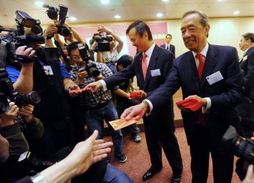 Ronald Arculli (R), former head of the Hong Kong Stock Exchange, hands out 'Lai See' or lucky money to journalists on the first trading day of the Year of the Rabbit in Hong Kong on February 7. He retired after six years in the position