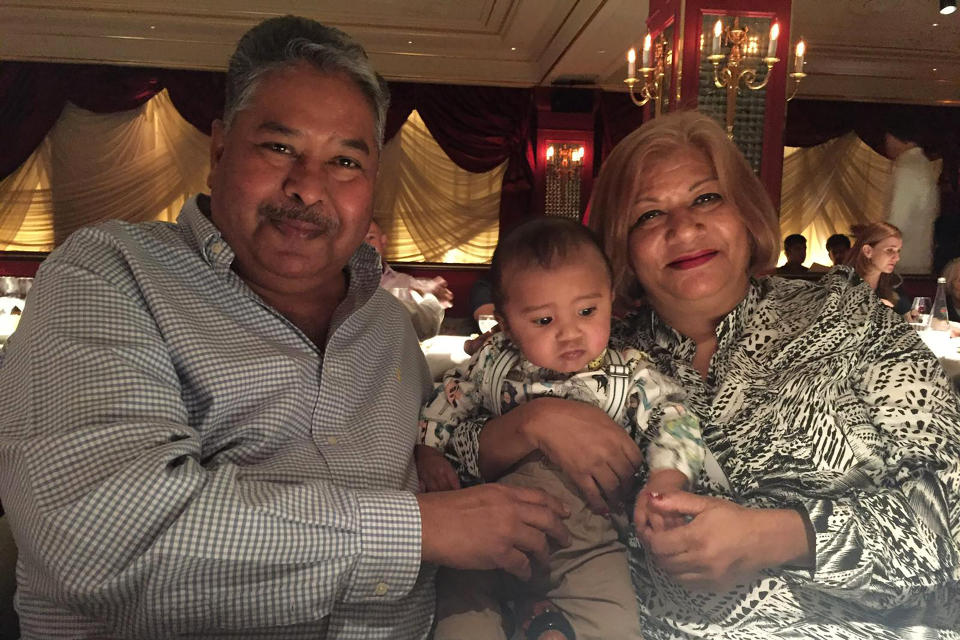 In this undated photo provided by Amrohi family, Yamini Amrohi, right, poses with her grandson and late husband Ashok Amrohi, who died of COVID-19, at a restaurant in London. Ashok, a medical doctor before joining the diplomatic corps, had traveled the world. He'd been ambassador to Algeria, Mozambique and Brunei, and had retired to Gurgaon, a city just outside the capital, and a life of golf and piano lessons. (Amrohi family via AP)