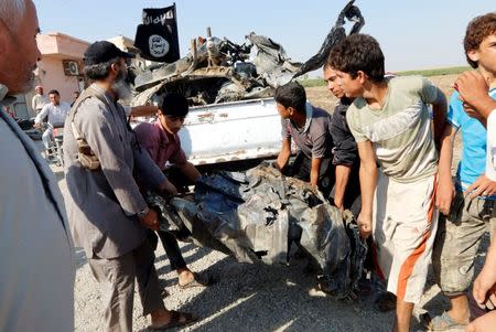 People carry a remnant of a war plane that crashed on the outskirts of Raqqa in northeast Syria September 16, 2014. REUTERS/Stringer