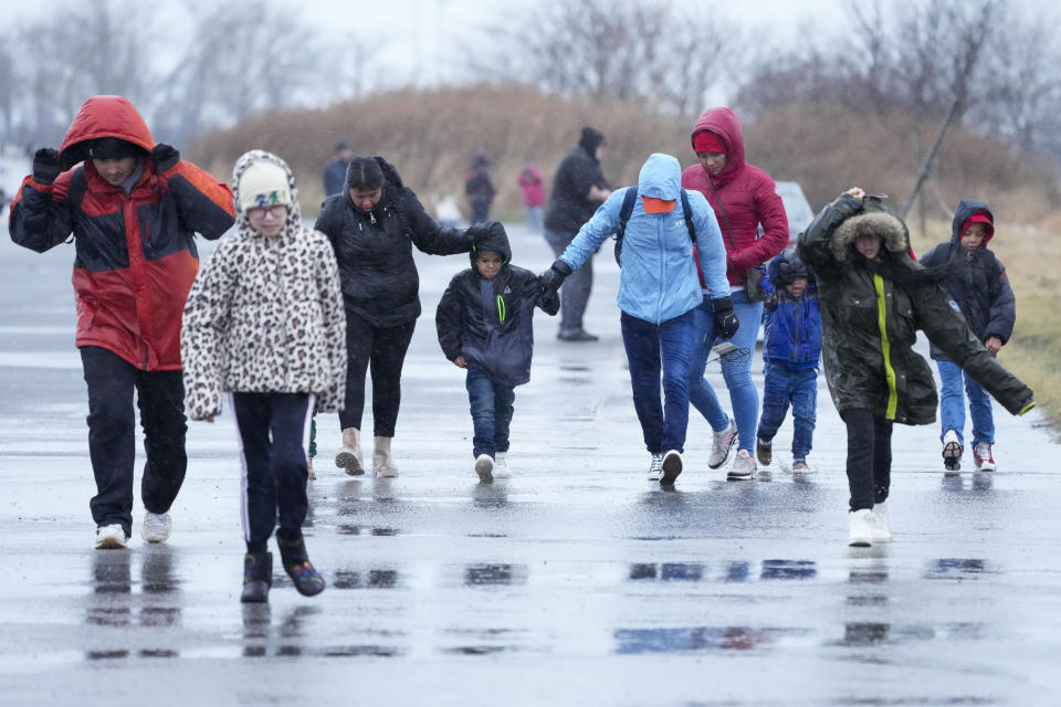Immigrants run in the rain towards the tents at migrant housing location at Floyd Bennett Field, Tuesday, Jan. 9, 2024, in New York. New York City will evacuate the nearly 2000 immigrants housed in tents at the site due to an impending storm. (AP Photo/Mary Altaffer)