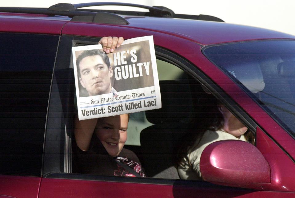 A passer-by holds up a special PM edition of the San Mateo County Times after the reading of the verdict that found Scott Peterson guilty of murder November 12, 2004, in Redwood City, California.