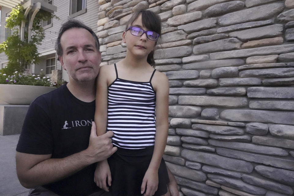 Independent voter Bill Mehlem with his daughter, McKenzie, pauses for a picture outside the Old Town Newhall Library in Santa Clarita, Calif., on Aug. 2, 2023. The stay-at-home dad recalls voting enthusiastically for Republican presidential nominee John McCain, but Mehlen said he saw no chance he would support Rep. Mike Garcia, in part because the congressman joined House Republicans who attempted to reject electoral votes from Arizona and Pennsylvania after the 2020 presidential election. (AP Photo/Damian Dovarganes)