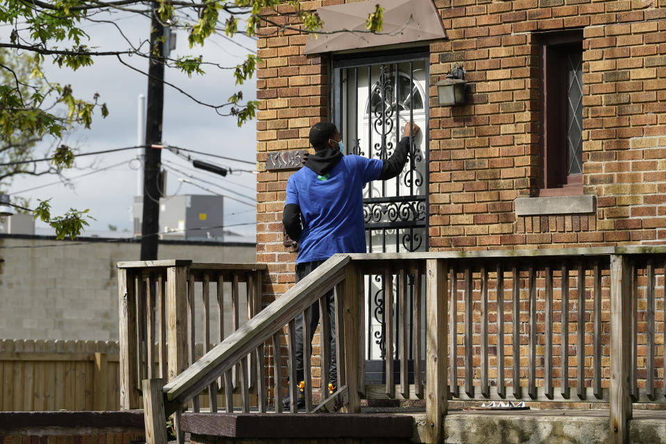 Sirgregory Allen knocks on a door before leaving a flyer on a home in Detroit, Tuesday, May 4, 2021. Officials are walking door-to-door to encourage residents of the majority Black city to get vaccinated against COVID-19 as the city's immunization rate lags well behind the rest of Michigan and the United States. (AP Photo/Paul Sancya)