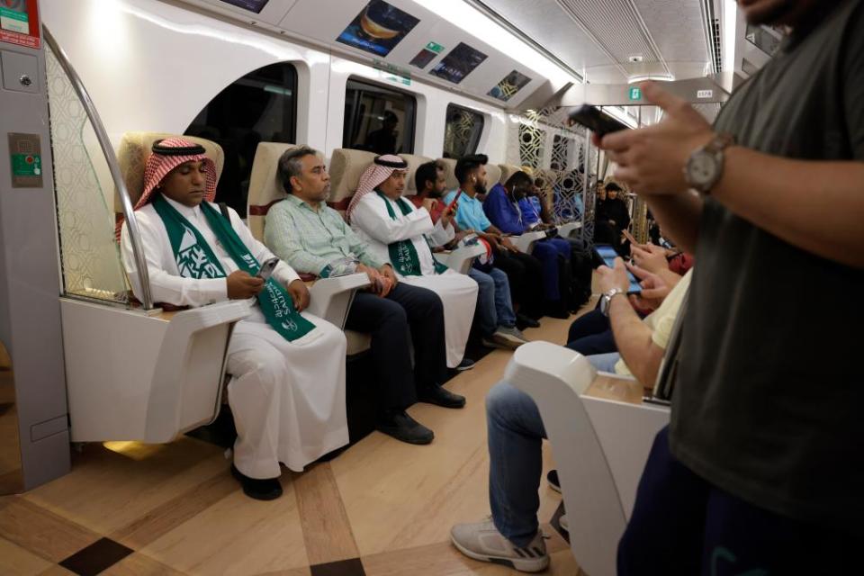 Saudi Arabian fans watching a match on their phones while sitting in the posh seats of the Gold Class carriage.