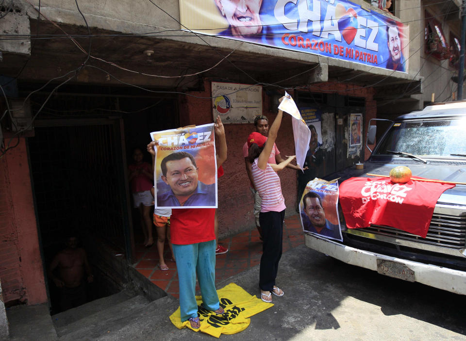 In this Sept. 16, 2012 photo, supporters of Venezuela's President Hugo Chavez wave campaign posters of him as opposition presidential candidate Henrique Capriles campaigns in the Petare shantytown of Caracas, Venezuela. From single mothers to construction workers, a segment of Chavez supporters have been turning away from the president and instead considering new leadership. They've become key to the Oct. 7 presidential vote and Capriles' strategy. (AP Photo/Fernando Llano)