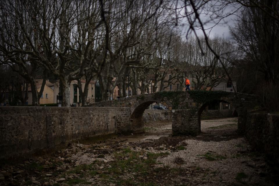 A man walks over a dried riverbed in Flassans-sur-Issole, southern France, Wednesday, March 1, 2023.