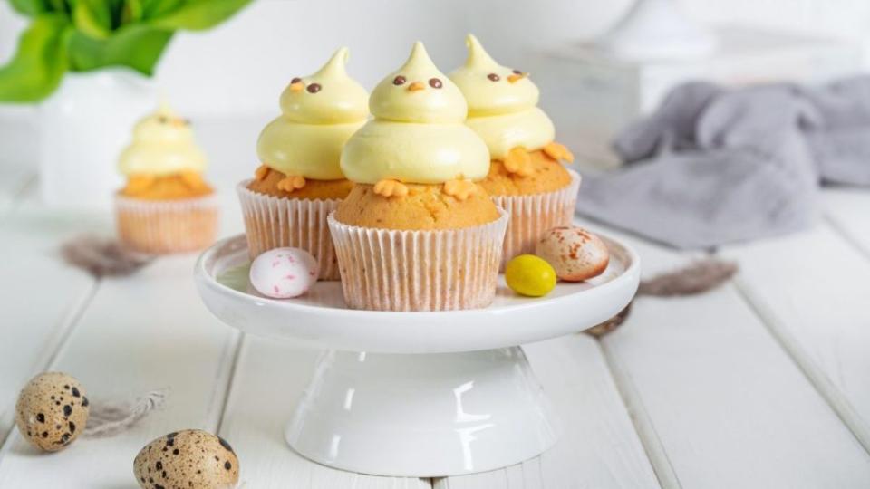 Cute Easter Chick Cupcakes.  Vanilla cupcakes with buttercream on a white stand with fresh flowers