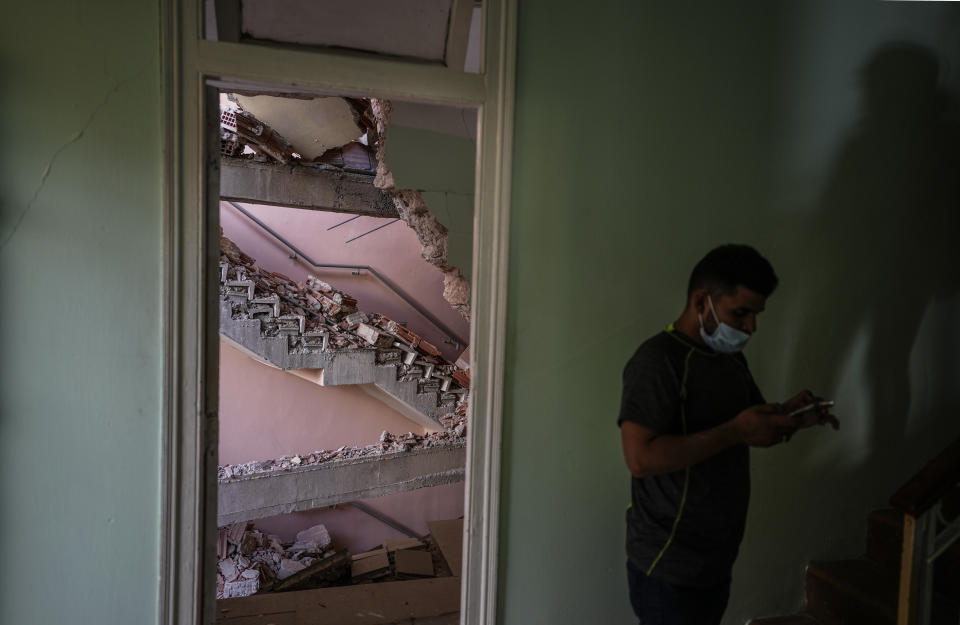 Rev. David Gonzalez looks at his phone standing next to a door that frames a damaged stairwell in the Hotel Saratoga as seen from inside the Calvary Baptist Church, also damaged by an explosion that devastated the hotel, in Old Havana, Cuba, Wednesday, May 11, 2022. The May 6th explosion killed dozens and badly damaged Cuba's most important Baptist church, which sits next door. (AP Photo/Ramon Espinosa)