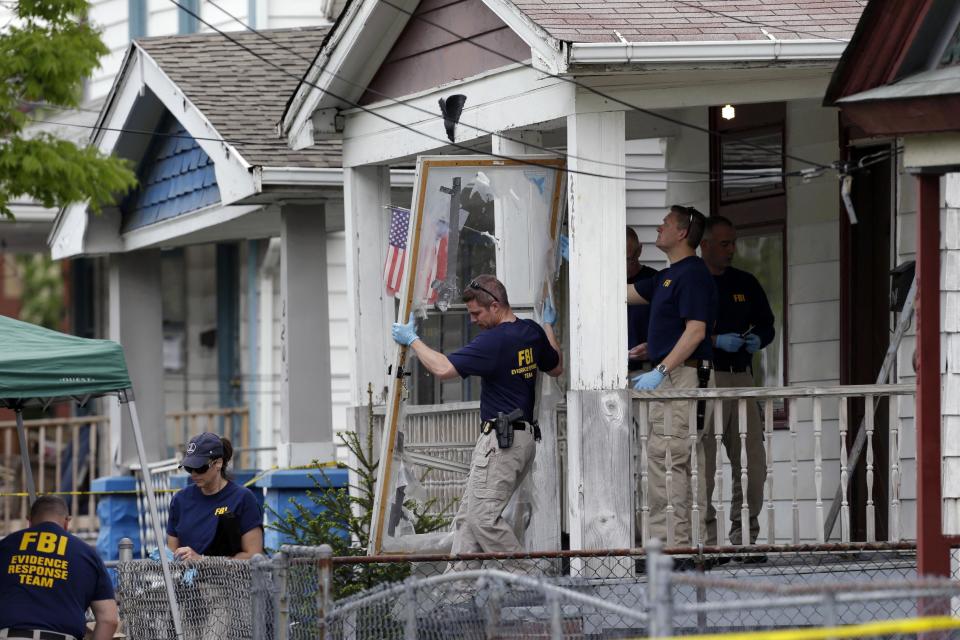 FILE - In this May 7, 2013 file photo, members of the FBI evidence response team carry out the front screen door from the Cleveland home of Ariel Castro, where three women escaped after 10 years of captivity. Amanda Berry broke through the screen door to freedom last May. Upstairs, officers found Gina DeJesus and Michelle Knight. They had been snatched off the streets separately between 2002 and 2004 and locked inside Castro’s house where he chained and raped them, investigators later said. (AP Photo/Tony Dejak, File)