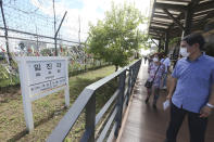 People wearing face masks to help protect against the spread of the new coronavirus pass by a directional sign showing the distance to North Korea's city Kaesong and South Korea's capital Seoul at the Imjingak Pavilion in Paju, near the border with North Korea, Sunday, July 26, 2020. North Korean leader Kim Jong Un placed the city of Kaesong near the border with South Korea under total lockdown after a person was found with suspected COVID-19 symptoms, saying he believes "the vicious virus" may have entered the country, state media reported Sunday. (AP Photo/Ahn Young-joon)