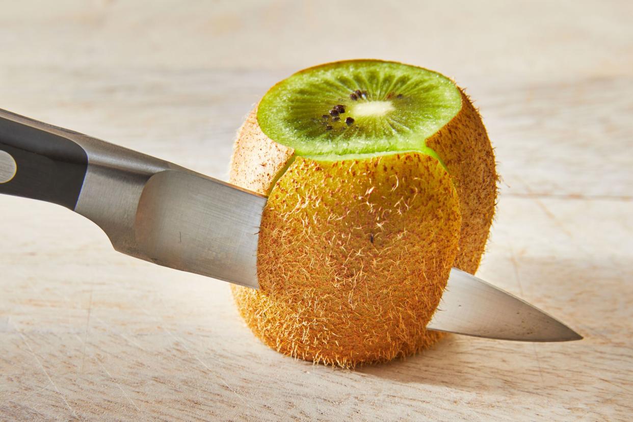 a knife is shown taking the skin off the edge of kiwi