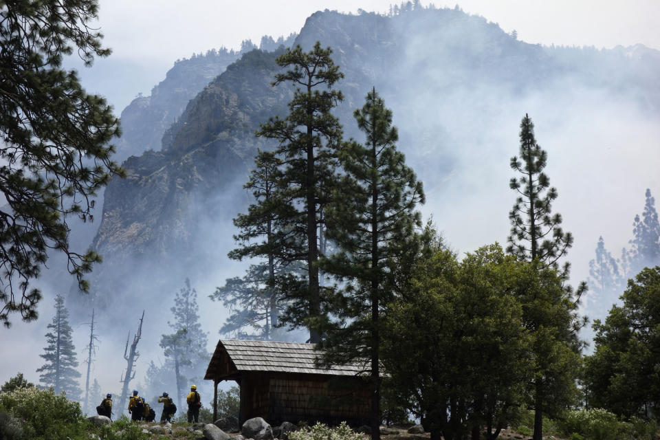 In this June 11, 2019 photo, firefighters prepare to protect Knapp's Cabin, a storage shed from the 1920s that is the oldest building in Cedar Grove, during a prescribed burn at Kings Canyon National Park, Calif. The prescribed burn, a low-intensity, closely managed fire, was intended to clear out undergrowth and protect the heart of Kings Canyon National Park from a future threatening wildfire. The tactic is considered one of the best ways to prevent the kind of catastrophic destruction that has become common, but its use falls woefully short of goals in the West. (AP Photo/Brian Melley)