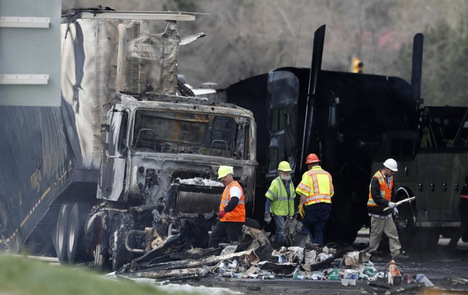 FILE - Workers clear debris from the eastbound lanes of Interstate 70 on April 26, 2019, in Lakewood, Colo., following a deadly pileup involving a semi-truck hauling lumber. A truck driver who was convicted of causing the fiery pileup that killed four people and injured six others on Interstate 70 west of Denver was sentenced Monday, Dec. 13, 2021, to 110 years in prison. Rogel Aguilera-Mederos was convicted in October of vehicular homicide and other charges stemming from the April 2019 crash. (AP Photo/David Zalubowski, File)