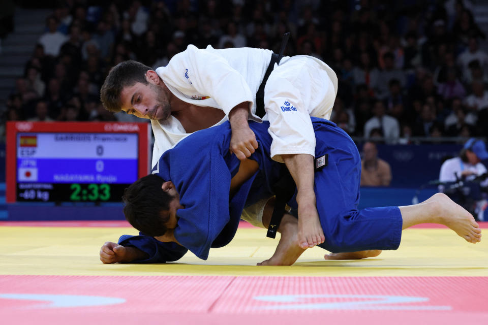 Spain's Francisco Garrigos and Japan's Ryuju Nagayama (Blue) compete in the judo men's -60kg quarter-final bout of the Paris 2024 Olympic Games at the Champ-de-Mars Arena, in Paris on July 27, 2024. (Photo by Jack GUEZ / AFP) (Photo by JACK GUEZ/AFP via Getty Images)