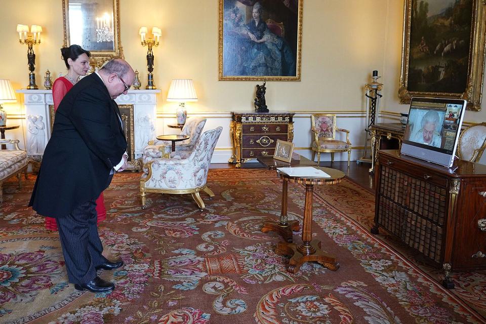 Britain's Queen Elizabeth II (R), in residence at Windsor Castle, appears on a screen via videolink during a virtual audience to receive Dr. Emmanuel Mallia, High Commissioner for the Republic of Malta, and his wife Elena Codruta, at Buckingham Palace in London on April 29, 2022.